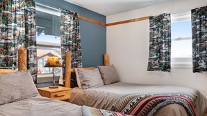 Une chambre avec deux lits, une table de chevet avec une lampe et des rideaux à motifs.