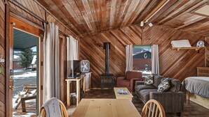 Indretning i en hyggelig træhytte med sofa, bord, seng, ventilator og pejs.
