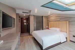 A modern hotel room with a bed, a TV, a wooden headboard, and a skylight.