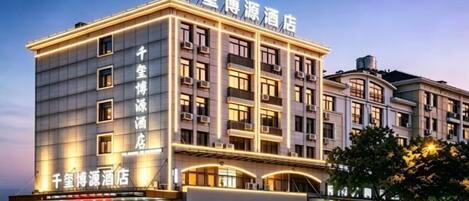 A multi-story hotel with a prominent sign at the top, multiple balconies, and a ground-level entrance with shops.