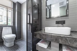 A modern bathroom with a toilet, a glass shower enclosure, a sink, and a mirror. - Yuehai Qianxi Boyuan Hotel (Yiwu International Trade City Branch) (Yiwu)