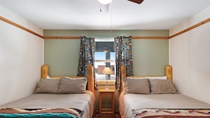 A twin room with two beds, a small table, and a window with curtains.