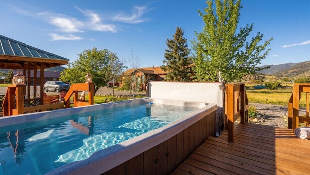 A hot tub on a wooden deck with a clear view of a mountainous landscape in the background.