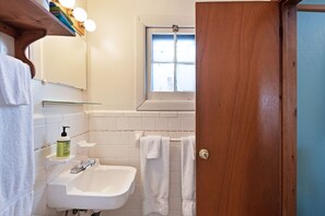 A bathroom with a white sink, a mirror, a window, and a wooden door. - Foothills Lodge 2 - South Fork (South Fork)