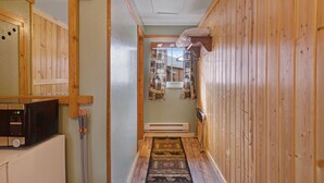A narrow hallway with wooden walls, a microwave on a counter, and a patterned rug. - Foothills Lodge 3 - South Fork (South Fork)