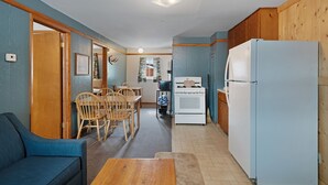 Cocina compacta con refrigerador, estufa y comedor con sillas y una mesa.