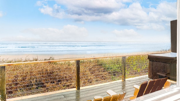 Een houten terras met uitzicht op zee en strand.