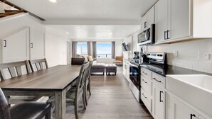 Une cuisine moderne avec des meubles blancs, une table à manger en bois et une vue sur l’extérieur.