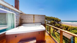 Une terrasse en bois avec un jacuzzi donnant sur une plage.