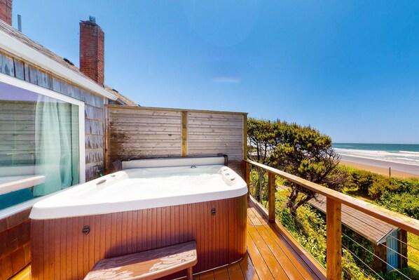 Une terrasse en bois avec un jacuzzi donnant sur une plage.