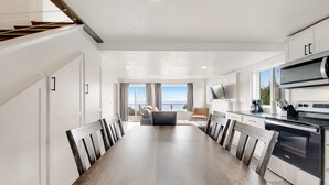 Une cuisine moderne avec un coin repas, de grandes fenêtres et une vue sur la mer.