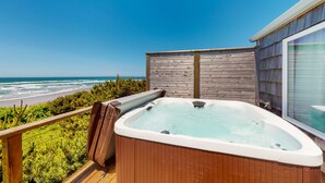 Una terraza de madera con un jacuzzi con vista a la playa.