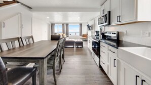 Una cocina moderna con armarios blancos, una mesa de comedor de madera y vistas al exterior.