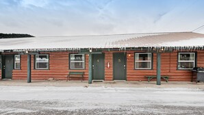 A row of log cabins with numbered doors, benches, and a gravel driveway.