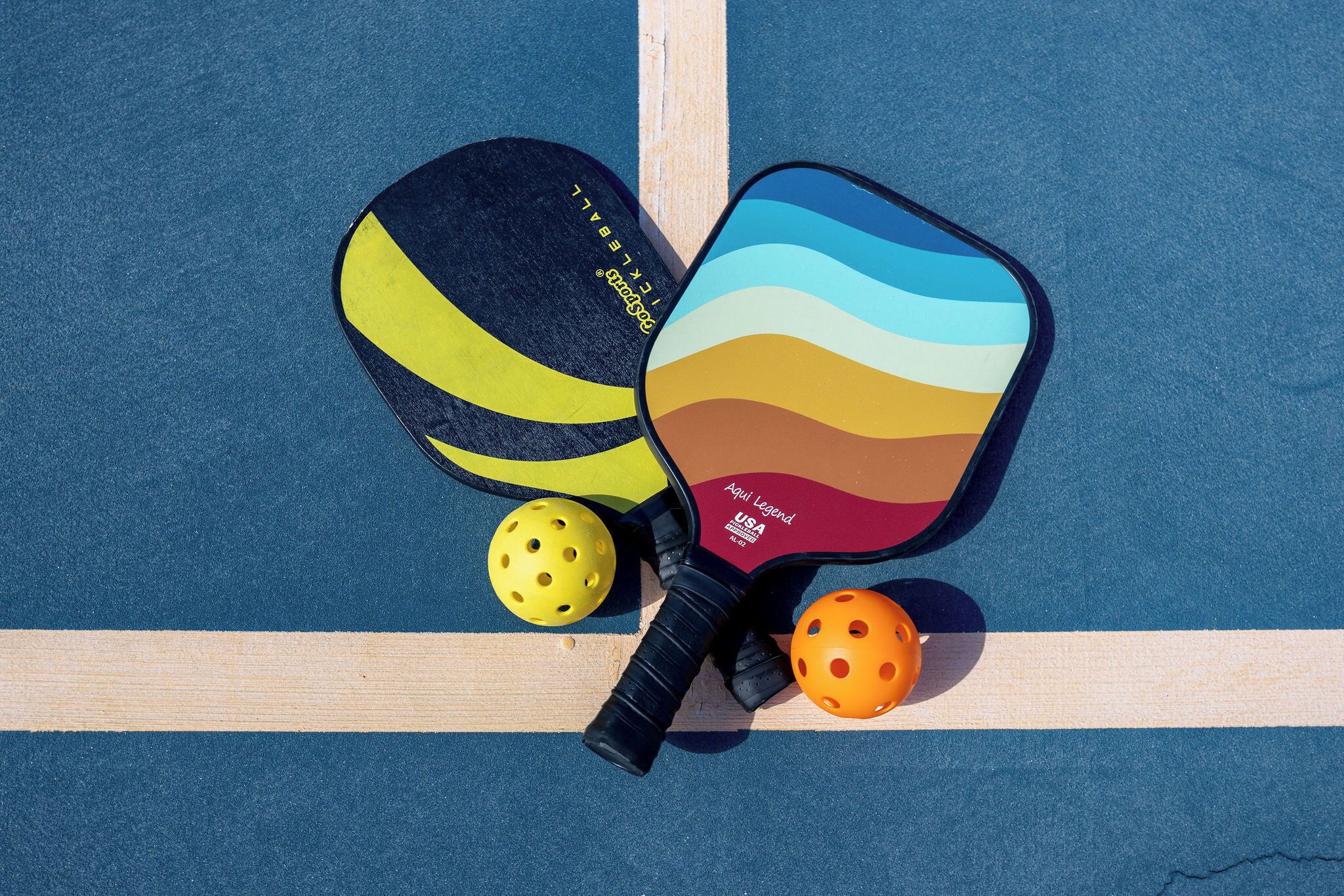 Una raqueta de bádminton, dos volantes y una paleta de colores sobre una cancha azul con líneas blancas.