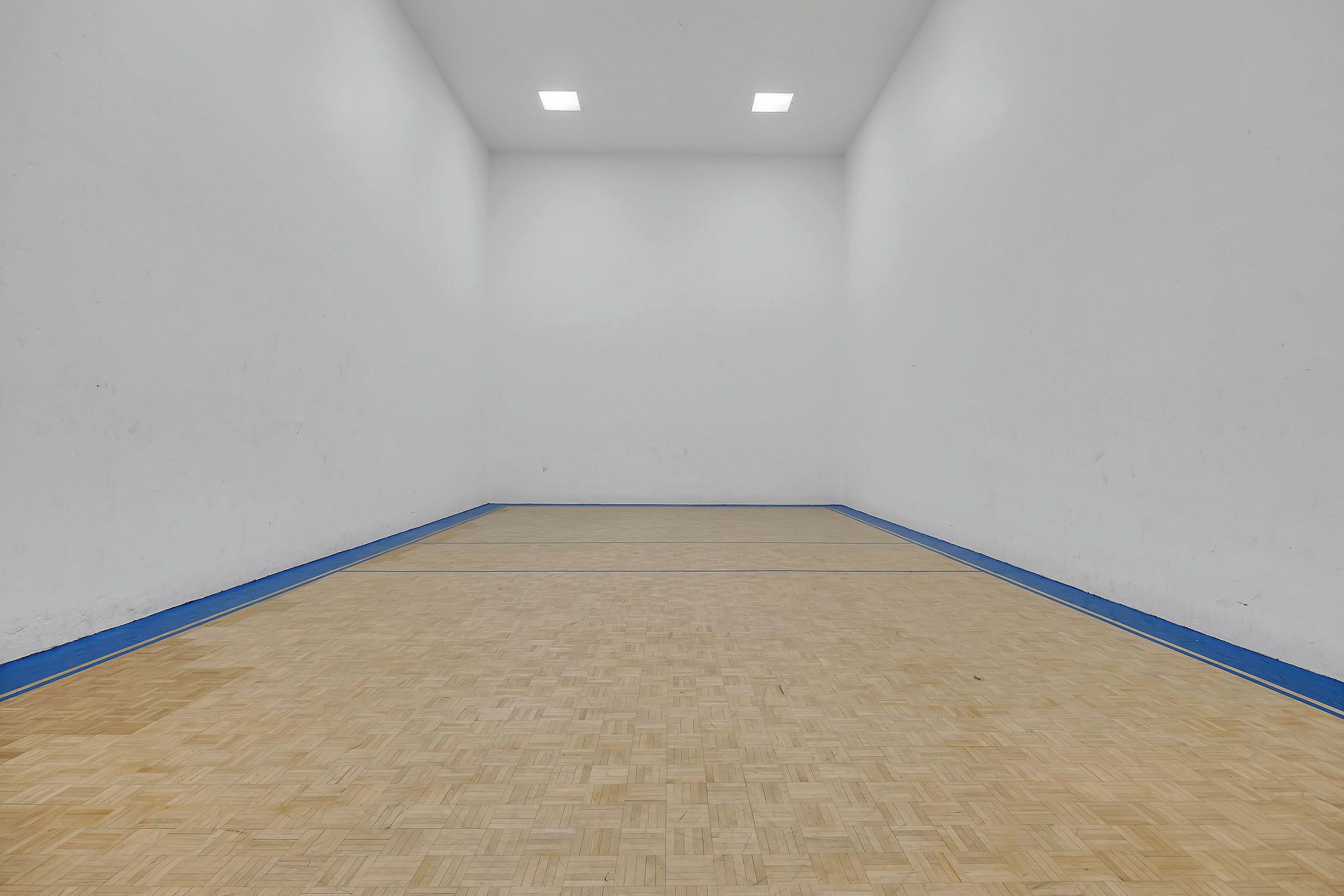 Quarto com piso de madeira, paredes brancas e uma faixa azul nas bordas.