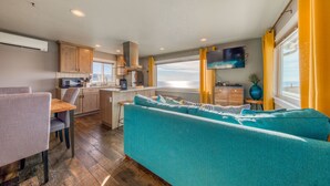 A compact living space with a kitchenette, a sofa, a dining area, and a TV mounted on the wall. - Oceanside Inn #6: Pet-free unit. No pets allowed. (Oceanside)