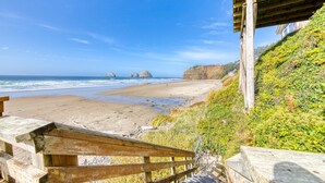 A wooden bench overlooking a beach with a clear view of the ocean and distant rocky formations. - Oceanside Inn #6: Pet-free unit. No pets allowed. (Oceanside)