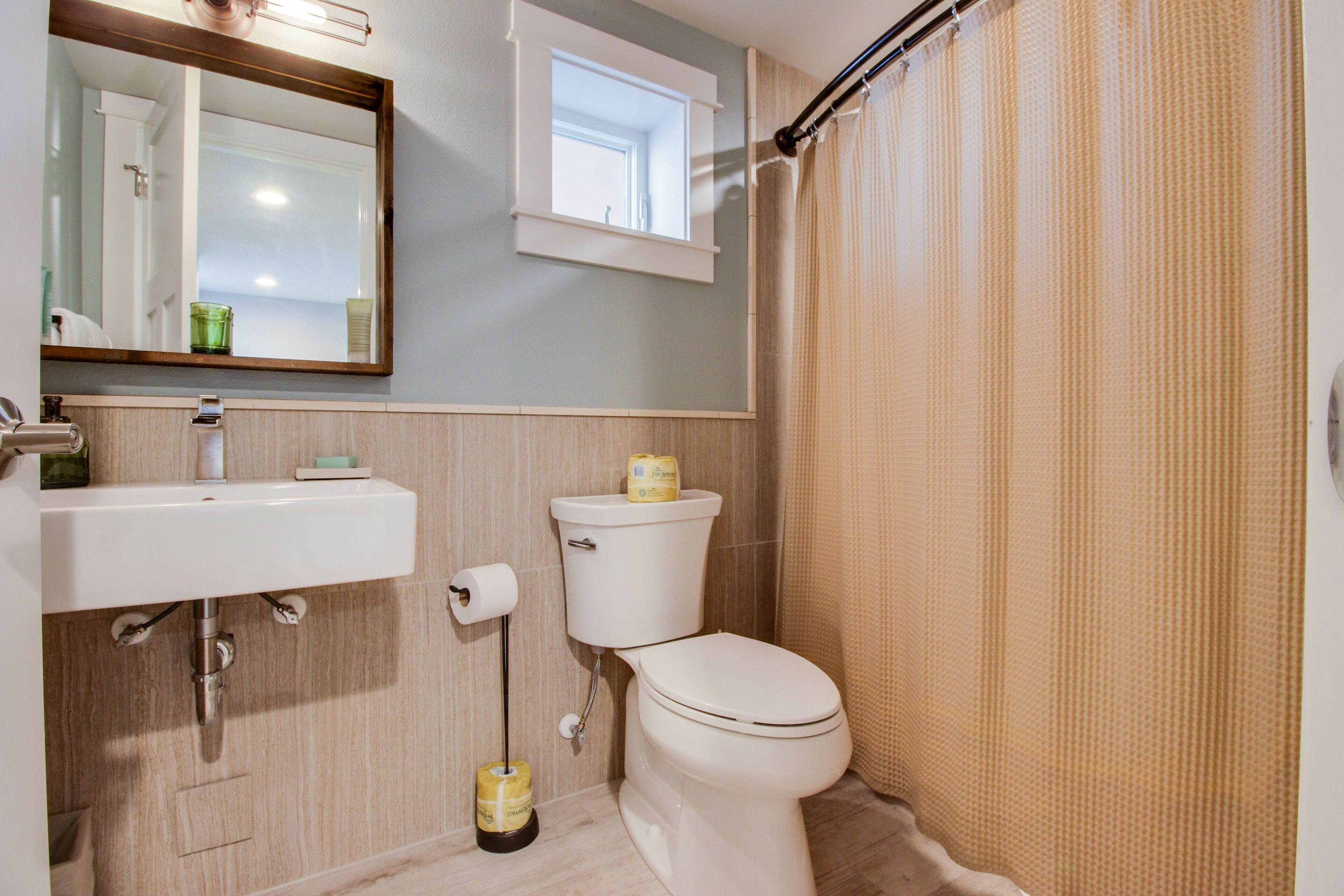 A bathroom with a sink, toilet, and a window above the toilet.