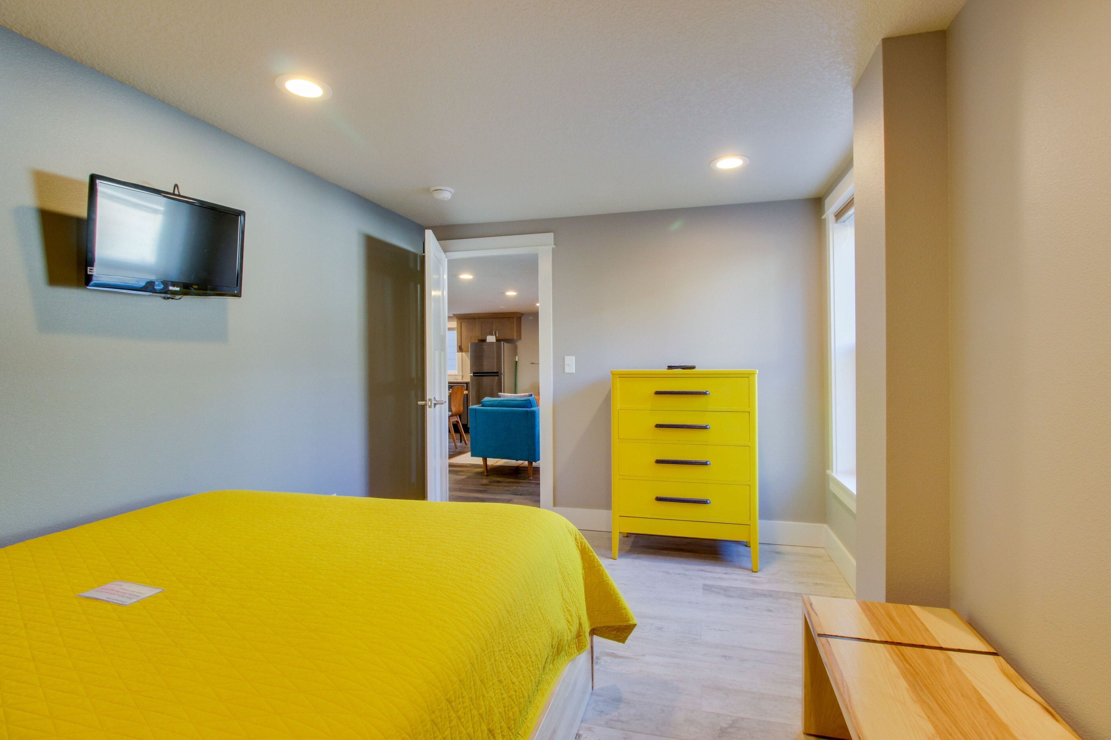 A bedroom with a bed, a television, a dresser, and a bench.