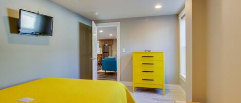A bedroom with a bed, a television, a dresser, and a bench.