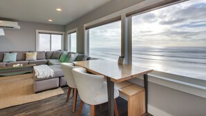 A modern living room with a large window, a sofa set, and a dining table. - Oceanside Inn 1: Pet-free unit. No pets allowed. (Oceanside)