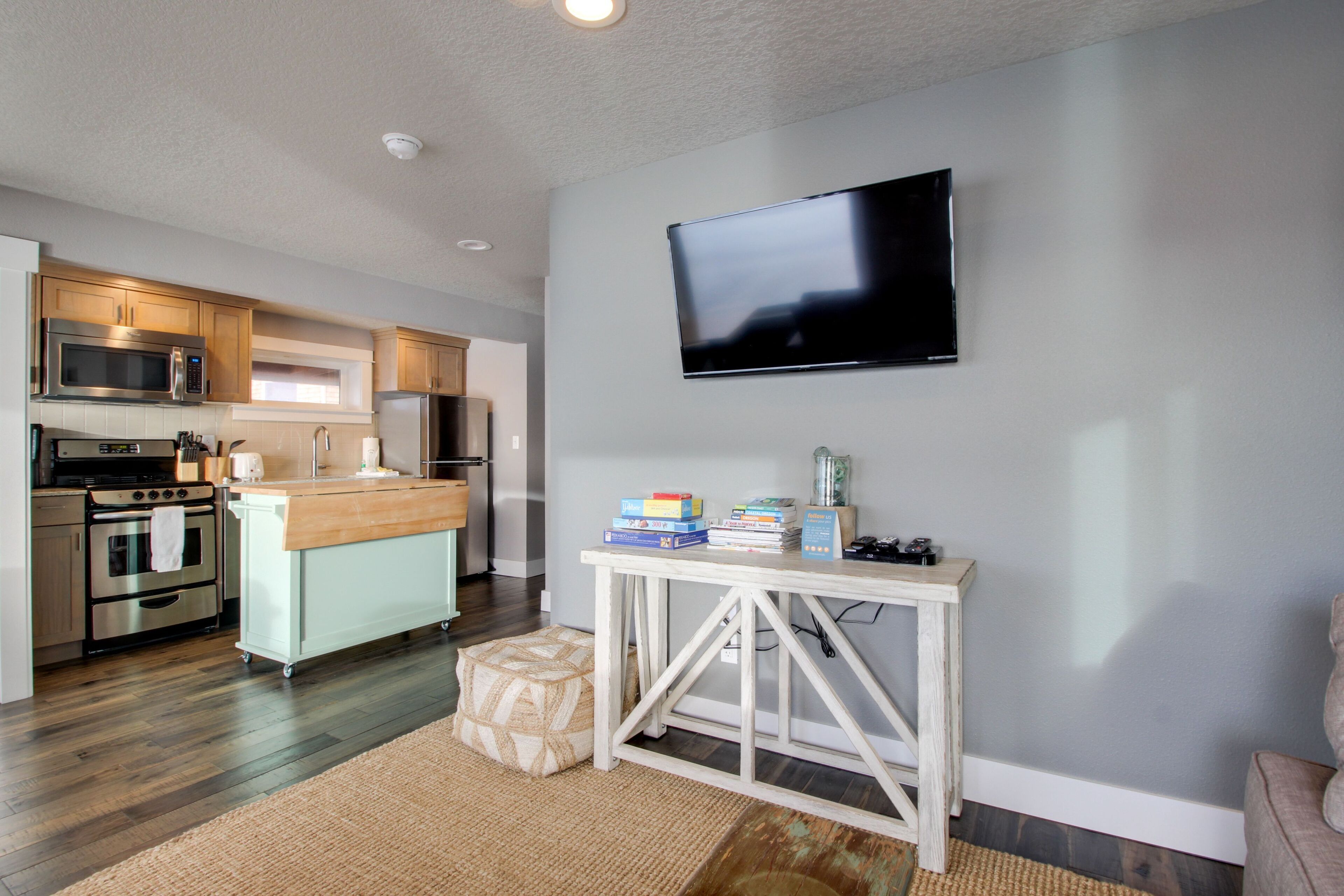A modern kitchen with stainless steel appliances, a wooden island, and a mounted flat-screen TV.