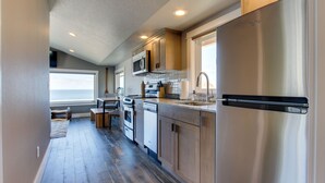 A modern kitchen with stainless steel appliances, wooden cabinets, and a large window providing natural light.