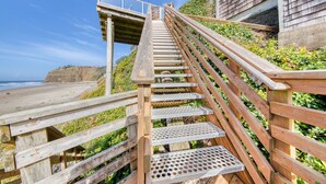 A wooden staircase leading to a beach with a clear view of the ocean.