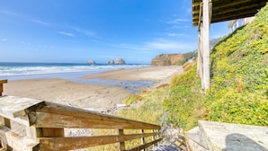 A wooden bench overlooking a beach with a clear view of the ocean and distant rocky formations.