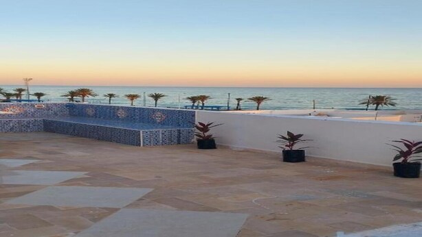 Una terrazza con vista sul mare, pavimento piastrellato e piante in vaso.
