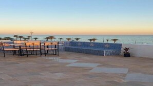 Un'area salotto all'aperto con vista sul mare, caratterizzata da un muro e un pavimento piastrellati.