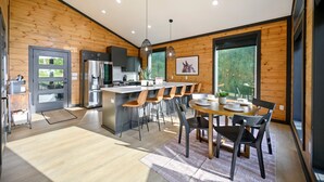 A modern kitchen with a central island, bar stools, and a dining table with chairs. - Couples ONLY + Spa Suite + Hot Tub + 3 Fireplaces - Escape to Whiskey Nights (Broken Bow)
