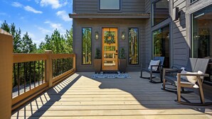A wooden deck with a railing, a front door with a wreath, and two chairs on the right side. - Couples ONLY + Spa Suite + Hot Tub + 3 Fireplaces - Escape to Whiskey Nights (Broken Bow)