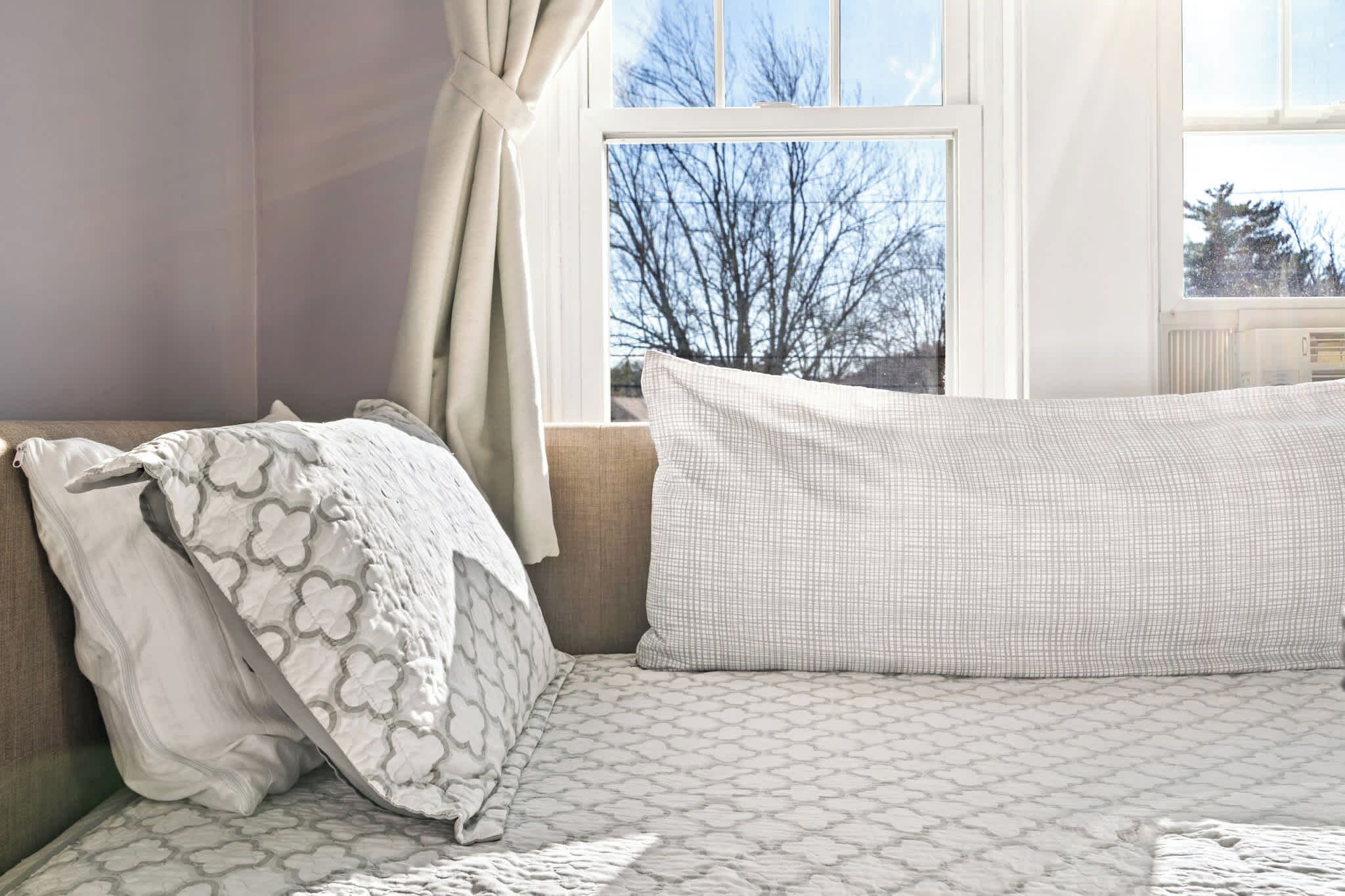 A bedroom with a bed, a window with a view of trees, and a curtain.
