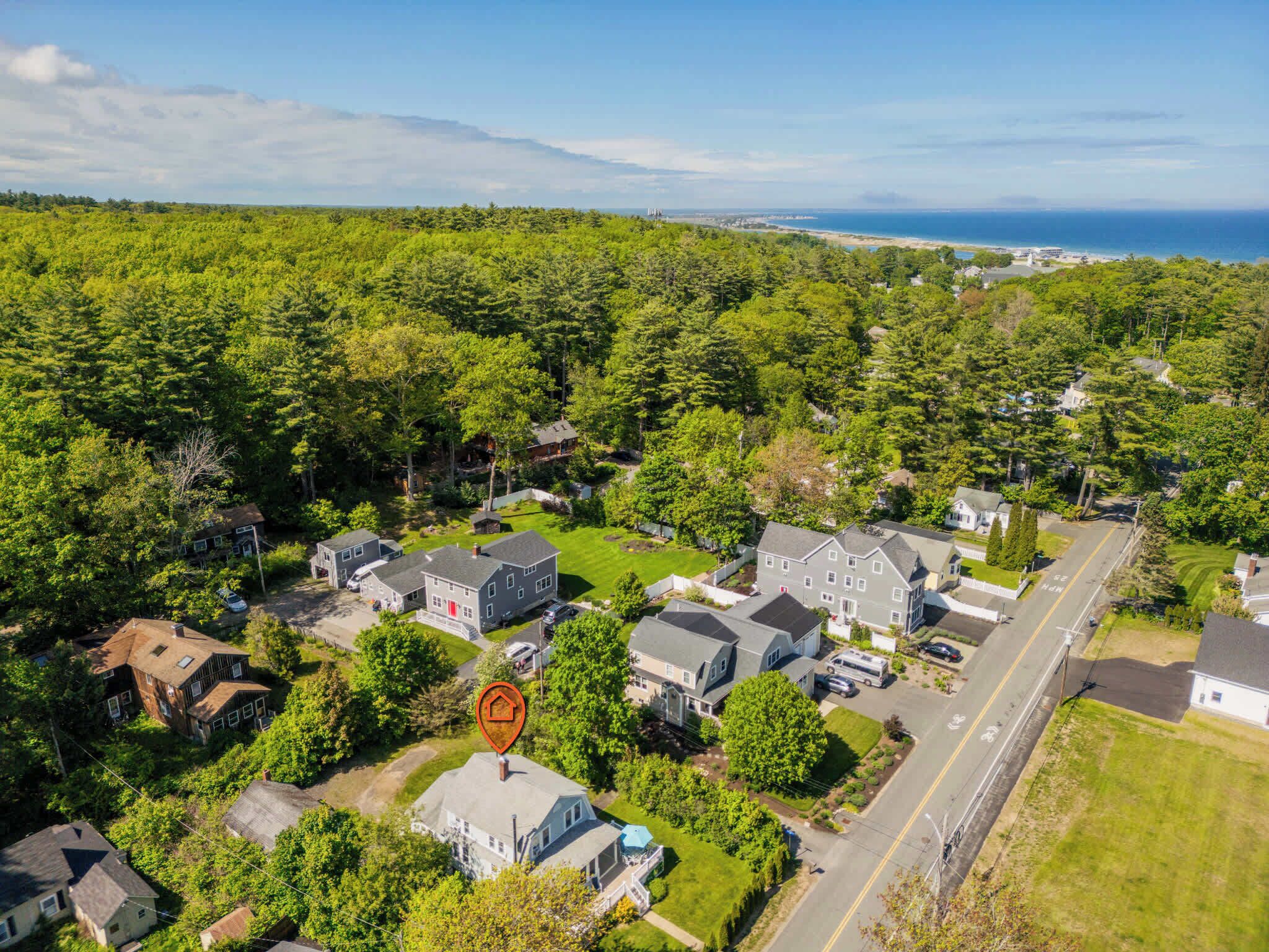 An aerial view of a residential area with houses, roads, and a body of water in the distance.