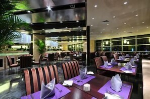 Un hall d’hôtel doté d’un espace salon central, d’une grande fenêtre et d’une plante.