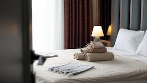 A neatly made bed with rolled towels, a bedside lamp, and a window with curtains. - Living Dream Duplex Belek (Antalya)