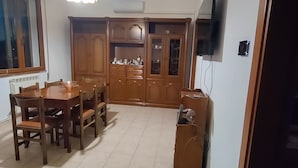 A dining area with a wooden table and chairs, a cabinet with glass doors, and a ceiling light fixture. - Cozy house in the Po Delta Park near the sea Belemi's House (Ca' Venier)