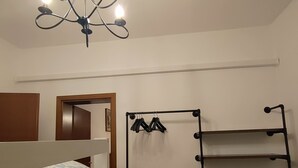 A room with a bunk bed, a hanging clothes rack, and a chandelier. - Cozy house in the Po Delta Park near the sea Belemi's House (Ca' Venier)
