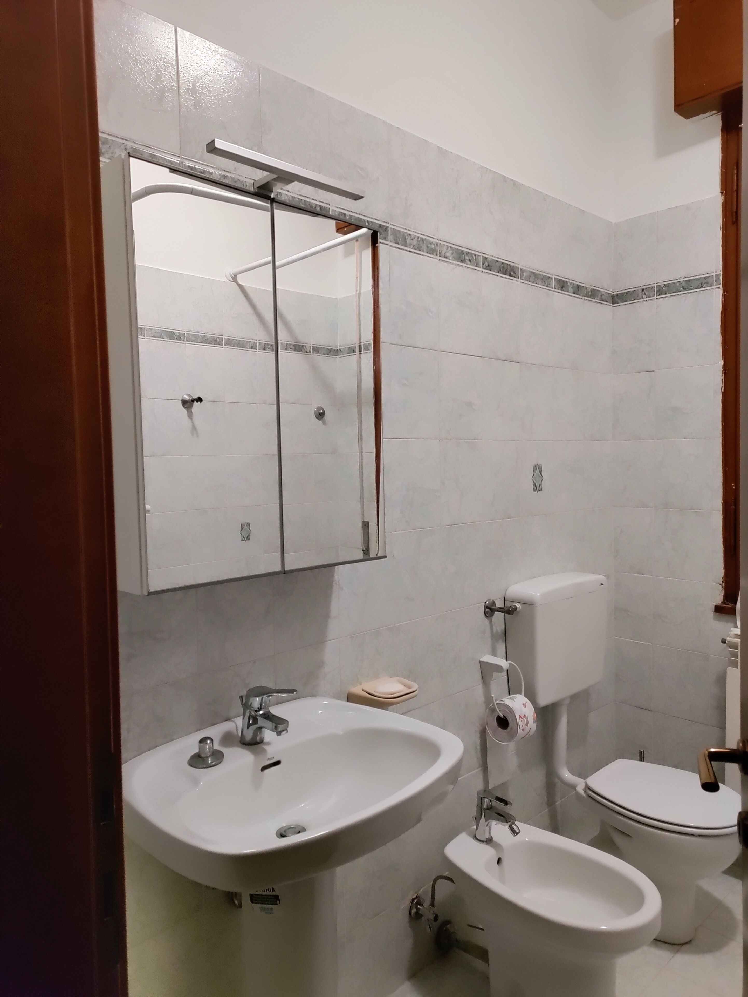 A bathroom with a white sink, a bidet, a toilet, and a mirror.