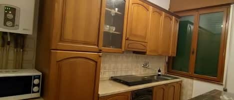 A kitchen with wooden cabinets, a microwave, a sink, and a chandelier.