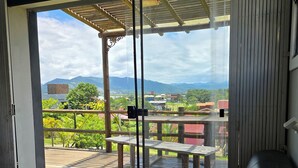 A balcony with a wooden deck, a black sofa, and a table. - Morada Aracuã (Imbituba)
