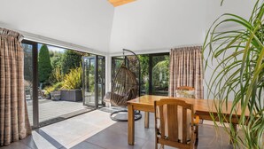Un comedor moderno con mesa y sillas de madera, ventanas amplias y una silla colgante.