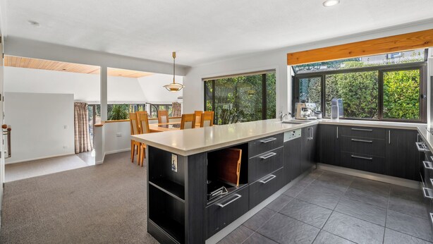 Una cocina moderna con armarios oscuros, una isla grande y vistas a zonas verdes.