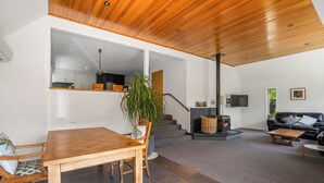 Un amplio espacio habitable con una mesa de comedor de madera, una escalera que lleva a una cocina y una zona de estar acogedora con chimenea.