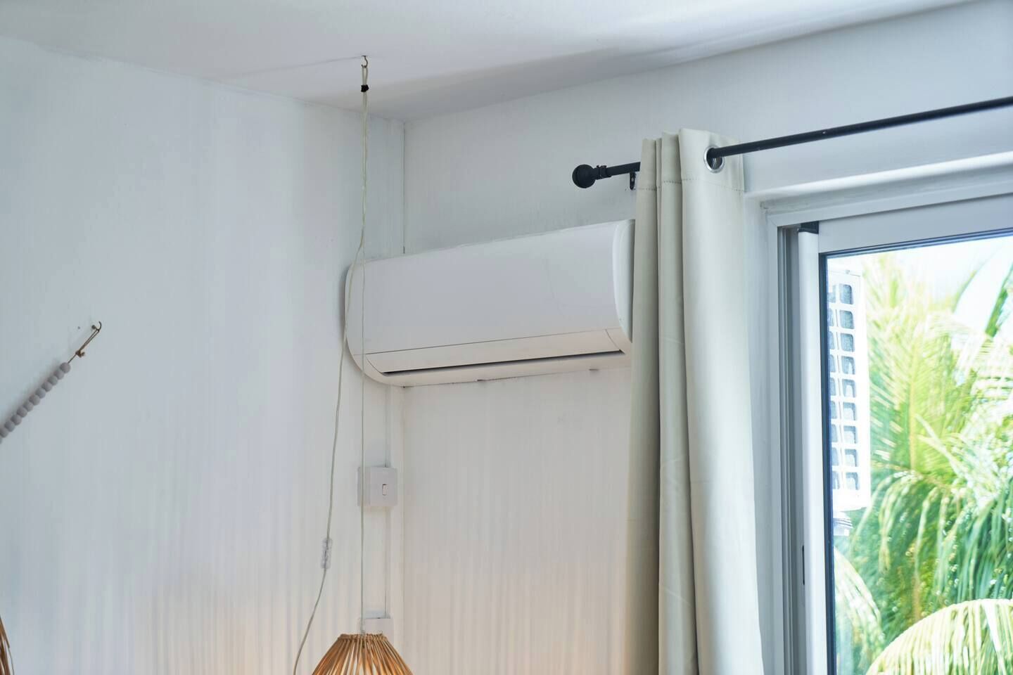 A room with a window, an air conditioning unit, and a curtain rod.