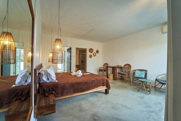 A bedroom with two beds, a sitting area with wicker furniture, and a large mirror.