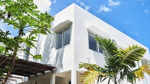 Un bâtiment moderne, de couleur blanche, doté de grandes fenêtres et d’un espace extérieur abrité.