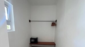 Une petite pièce étroite aux murs blancs, avec un banc en bois, un porte-manteau et une petite étagère sur laquelle se trouve une radio.